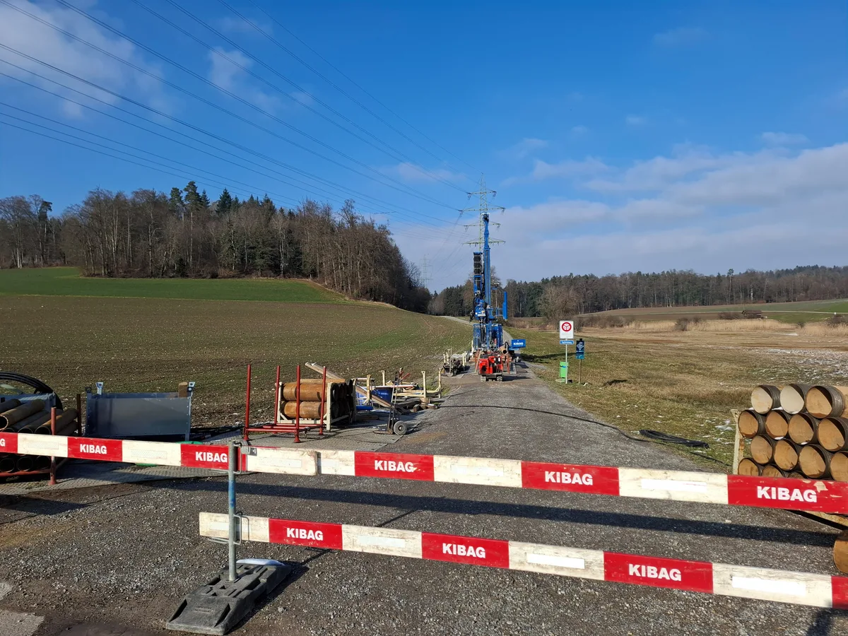 Man sieht eine Baustelle und eine grosse Bohrmaschine auf einem Landweg. 